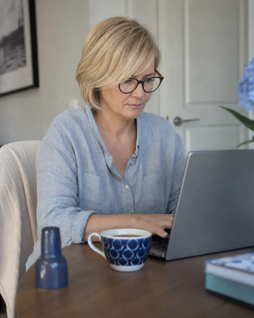 Kobieta w domu wypełnia wywiad medyczny na laptopie, ekran zwrócony do niej